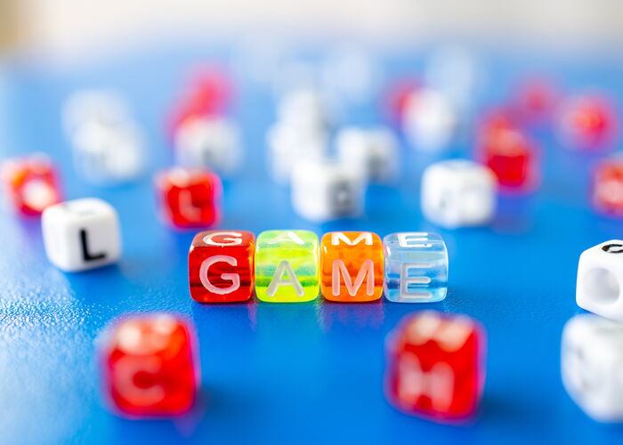 Photo : Un ensemble de dés étalés sur une table avec 4 dés au milieu qui forme le mot GAME